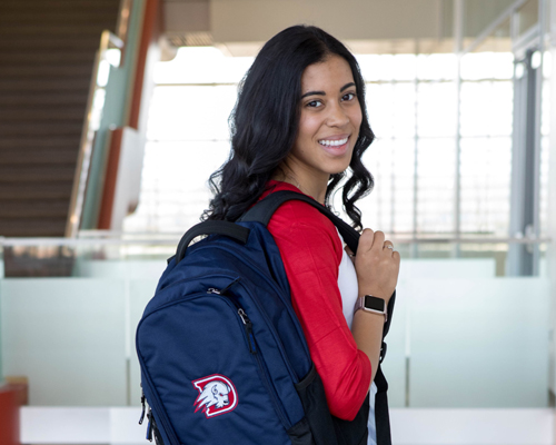 student with backpack smiling at camera